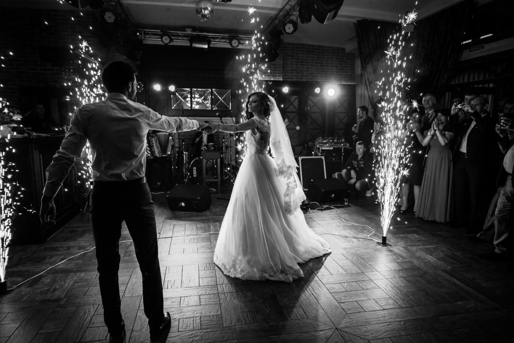 Beautiful newlywed couple first dance at wedding reception surrounded by smoke and lights and sparks b&w