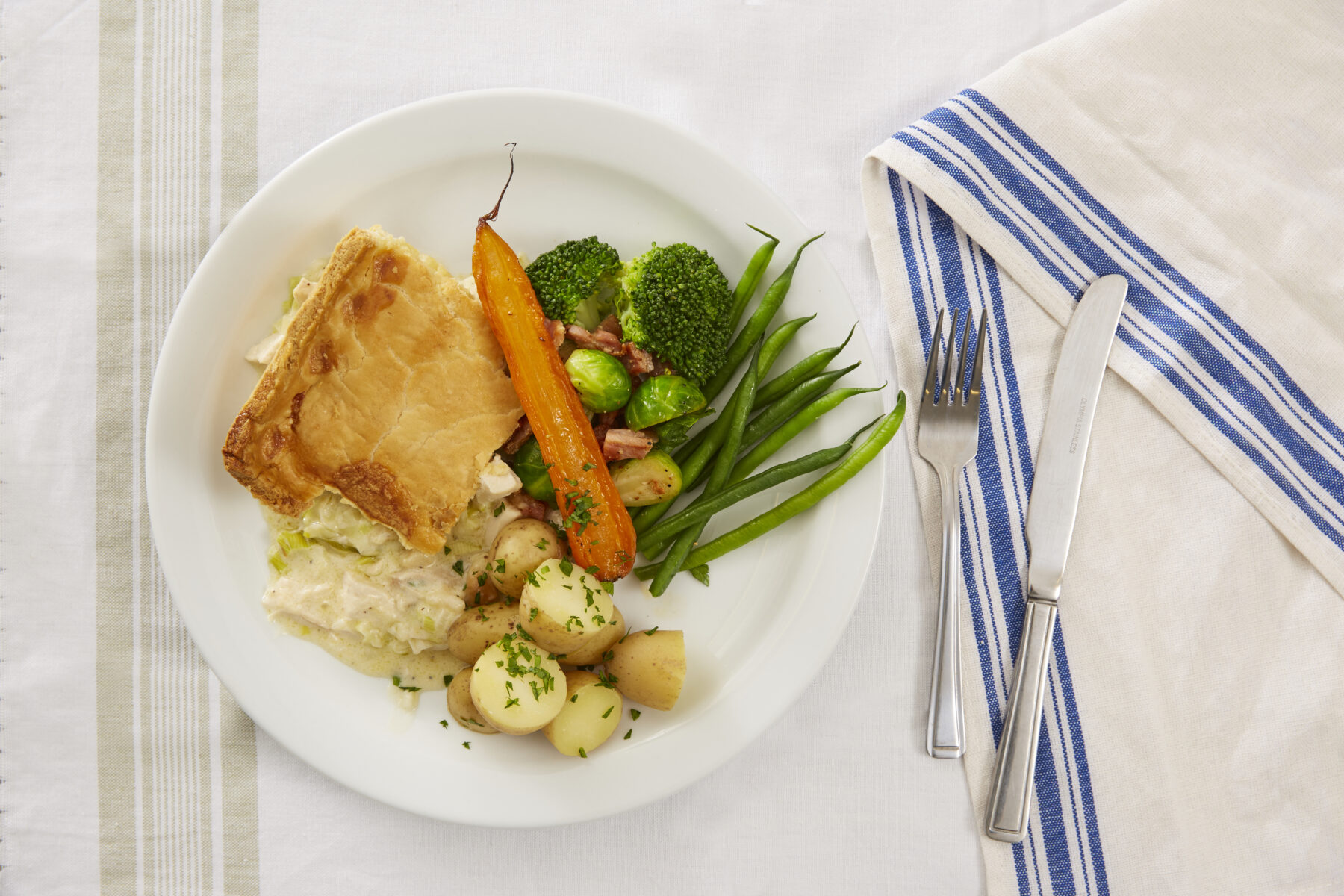 A golden sharing pie with new potatoes and seasonal vegetables.
