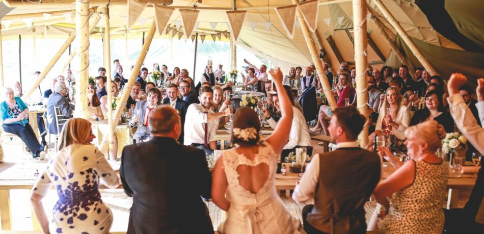 Happily married couple with guest watching cheering to a gorgeous evening wedding breakfastt
